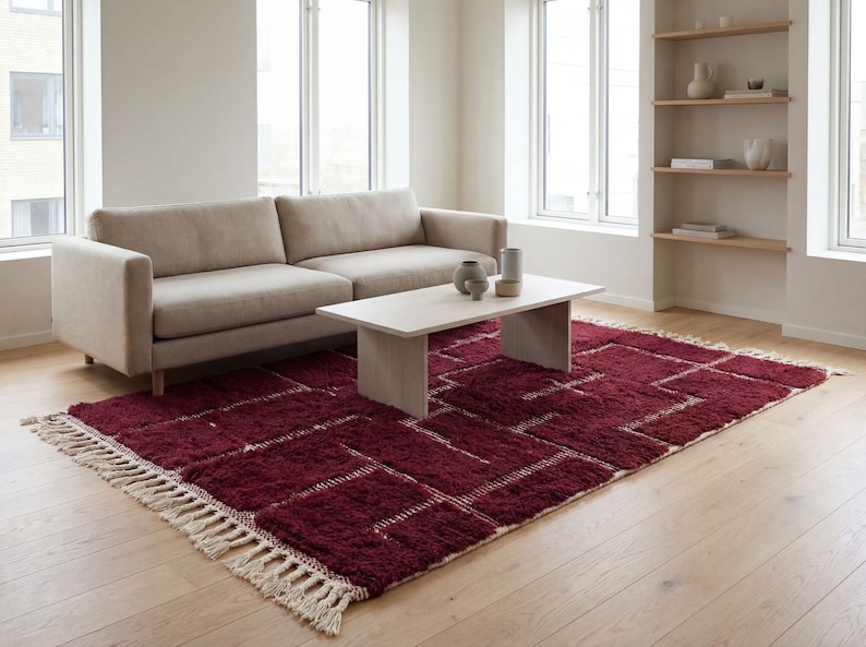 Deep red wool rug handcrafted in Morocco with thick textured pile and rich natural fibers. This handmade area rug features a warm deep red tone, soft plush surface, and subtle Berber-inspired design. Ideal for living rooms or bedrooms, the rug adds warmth, depth, and authenticity while offering durable, eco-friendly wool construction and customizable sizing.