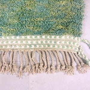Close-up of hand-knotted fringe and mint green edge finish – traditional Moroccan rug made with natural wool