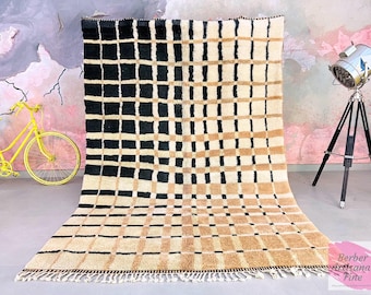 Könnte beinhalten: Ein schwarz-beiger Schachbrettteppich mit Fransenbordüre. Der Teppich ist aus Wolle und hat eine weiche, plüschige Textur.