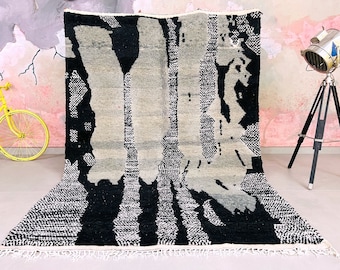 May include: Black and white abstract rug with a geometric pattern. The rug has a fringe border.