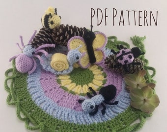 May include: A crochet pattern for a colorful garden-themed play mat with a variety of crocheted animals including a bee, butterfly, snail, spider, and ant. The mat is made with green, blue, pink, and yellow yarn. The text "PDF PATTERN" is visible in the top right corner of the image.