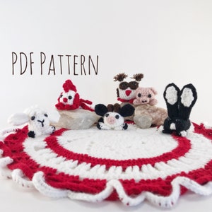 Puede incluir: Patrón PDF para tejer al crochet un conjunto de animales de granja en miniatura, que incluye una vaca, un cerdo, un conejo, un gallo y una oveja. Los animales están dispuestos sobre un encaje de ganchillo blanco y rojo.