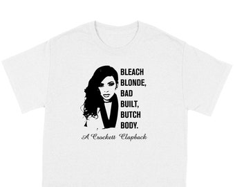 May include: White t-shirt featuring a black and white graphic of a woman's silhouette with the words "BLEACH BLONDE, BAD BUILT, BUTCH BODY." Below the graphic is the text "A Crockett Clapback."