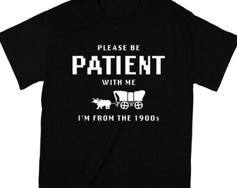 May include: Black t-shirt with white text that reads "Please be patient with me I'm from the 1900s". A white pixelated image of a covered wagon pulled by an ox is below the text.