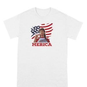 May include: White t-shirt with a graphic of a man with long hair and a beard, wearing a red, white, and blue bandana, holding up a rock and roll hand gesture. The graphic is in front of a distressed American flag with the word "MERICA" printed below.