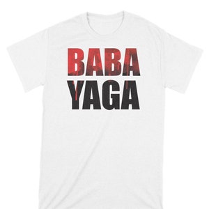 Puede incluir: Camiseta blanca con el texto "BABA YAGA" impreso en letras negras y rojas. Las letras están estilizadas con un efecto de goteo.
