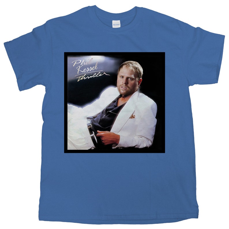 以下が含まれることがあります： 前面にフィル・ケッセルの白黒画像がプリントされた青いTシャツ。画像は彼のアルバム「スリラー」からのものです。
