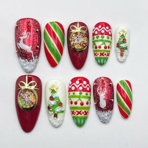 May include: A set of ten Christmas-themed nail art designs. The nails feature red, green, and white colors with festive patterns like stripes, reindeer, Christmas trees, and ornaments. Some nails have gold accents.