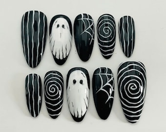 May include: Set of ten black and white Halloween-themed press-on nails. The nails feature different designs including ghosts, spiderwebs, and swirls.