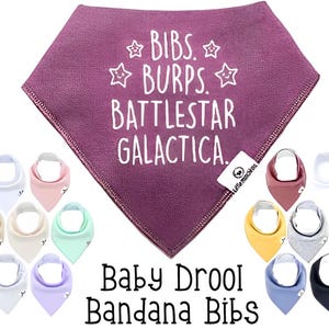 May include: Purple bandana bib with white text that reads "Bibs. Burps. Battlestar Galactica."  The bib is surrounded by a variety of colored bandana bibs.