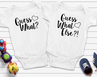 May include: Two white baby onesies with black text. The onesie on the left says "Guess What?" with a heart. The onesie on the right says "Guess What Else?!" with a heart.