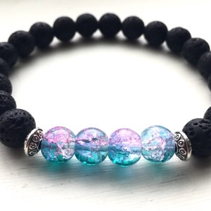 May include: A black lava rock bracelet with four iridescent glass beads in shades of blue and pink.