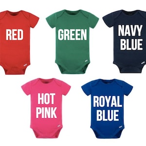 May include: Five baby onesies in red, green, navy blue, hot pink, and royal blue. Each onesie features the colour name printed in large white letters. The onesies are short-sleeved and have a simple, classic design.