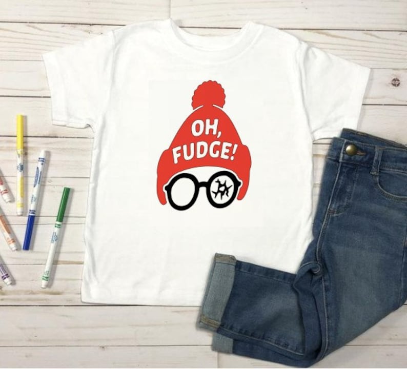 May include: White t-shirt with a red hat and glasses graphic. The graphic includes the text "OH, FUGE!". The shirt is paired with blue denim jeans. Colorful markers are scattered around the shirt.
