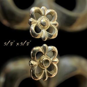 May include: Two gold-toned metal decorative hardware pieces with a floral design. Each piece measures 5/8 inches by 5/8 inches.