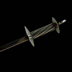 May include: A silver-toned letter opener with a decorative, twisted handle and two star-shaped accents. The blade is a flat, rectangular shape. The opener is set against a black background.