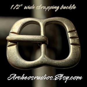 May include: A silver-toned metal buckle for 1 1/2 inch wide straps. The buckle has a simple, rectangular design with rounded edges.