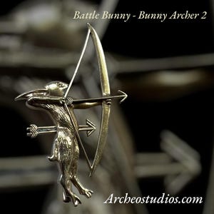 May include: A bronze-colored figurine of a rabbit archer, holding a bow and arrow. The rabbit is in a dynamic pose, with the arrow drawn back. The text "Battle Bunny - Bunny Archer 2" is at the top, and "Archeostudios.com" is at the bottom.