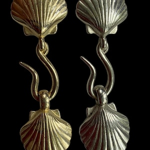 May include: A pair of dangling earrings featuring a gold-toned shell at the top connected by a curved hook to a matching gold-toned shell at the bottom, and a second pair featuring a silver-toned shell at the top and a silver-toned shell at the bottom.