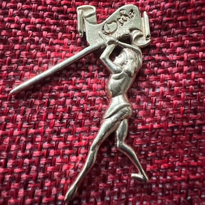 May include: Silver-toned metal charm depicting a person playing a trumpet. The charm is detailed and has a textured surface.