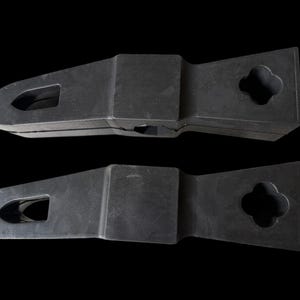 Puede incluir: Componentes de hardware negros de forma geom&eacute;trica con un ojo de cerradura y un dise&ntilde;o de tr&eacute;bol de cuatro hojas. Los componentes est&aacute;n apilados sobre un fondo negro. Los componentes parecen estar hechos de pl&aacute;stico duro o goma.