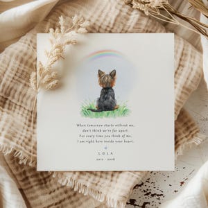 May include: A square card featuring a watercolour illustration of a small dog sitting in grass beneath a rainbow. The card includes the text "When tomorrow starts without me..." and the name "LOLA" with dates.