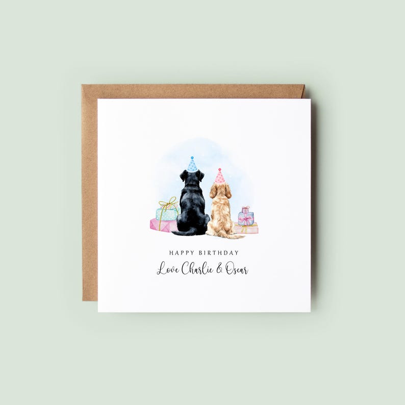Pu&ograve; includere: Un biglietto di compleanno con illustrazioni ad acquerello di due cani con cappelli da festa, seduti schiena contro schiena. Il biglietto dice "Happy Birthday" e "Love Charlie & Oscar". Il biglietto &egrave; su una busta marrone.