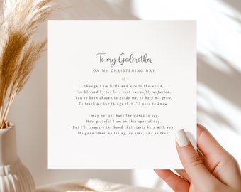 May include: A white card with the text "To my Godmother" and a poem about a christening. The card is held by a person with a light background and dried flowers in a vase.