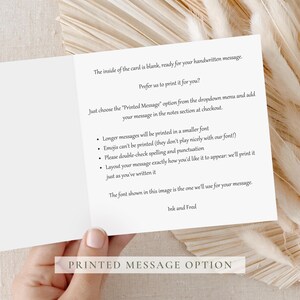 Minimalist second wedding anniversary card with a soft beige number “2” and the text “Two years down” and “FOREVER TO GO”, photographed on a white square card on a heart patterned background with ribbon in neutral tones.