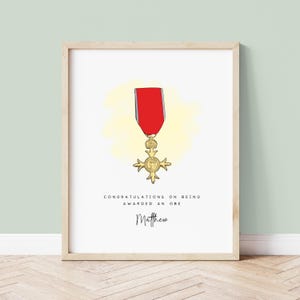 May include: A white printable card with a gold and red OBE medal illustration. The text reads "Congratulations on being awarded an OBE Matthew".