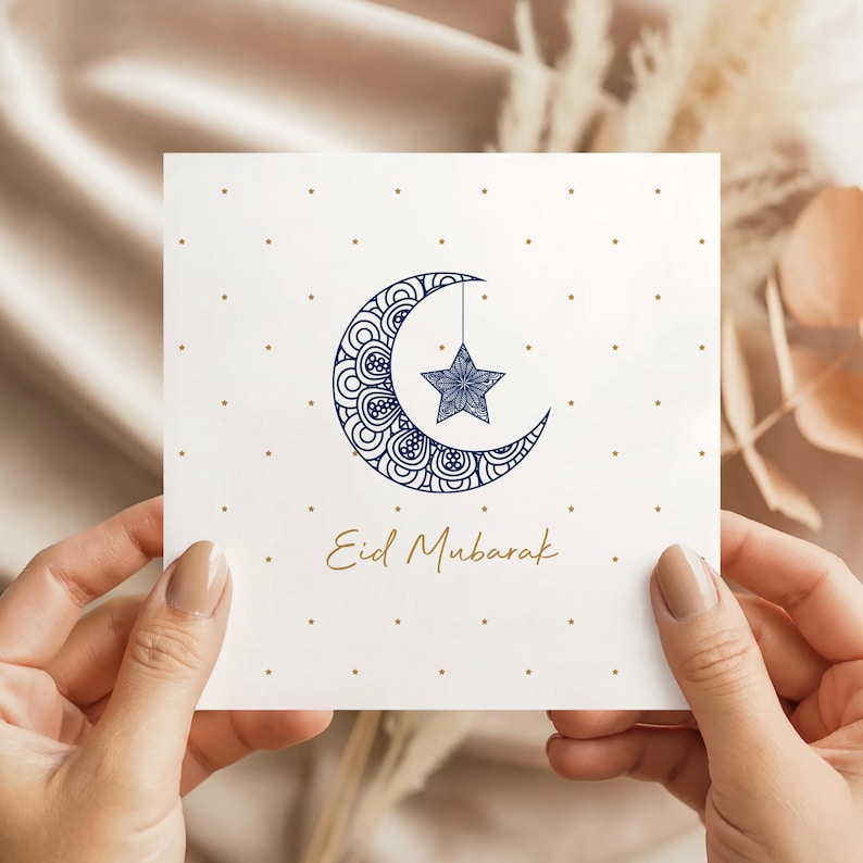 Elegant square Eid Mubarak card with a navy patterned crescent moon and hanging star, dotted gold stars on a white background and Eid Mubarak text in gold script.