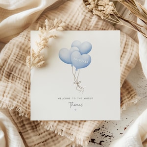 Personalised new baby boy card with blue heart balloons and birth date, featuring the name “Thomas” and soft neutral styling – a keepsake welcome to the world card.