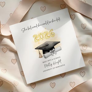 Peut inclure: Une carte de remise de diplôme carrée avec le texte She believed she could so she did, l'année 2026 en doré, une toque noire et un diplôme enroulé. En dessous, le texte indique BASC ARTS & SCIENCE, Molly Knight et University of Newcastle.