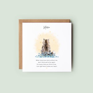 Square white cat loss sympathy card with yellow watercolour background, personalised back-view cat illustration and remembrance poem, supplied with a white plantable seed paper heart embedded with forget-me-not and poppy seeds, kraft envelope behind on a soft green background.