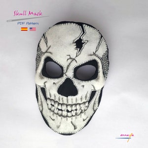 Op de afbeelding: Een wit vilt schedelmasker met een gebarsten ontwerp en zwarte stiksels. Het masker heeft een gestikte zwarte mond en oogkassen. De tekst "Skull Mask" en "PDF Pattern" is zichtbaar boven het masker.
