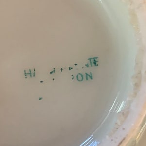 May include: Close-up of a green stamp on a white surface that reads "HI ... TE ... DON".