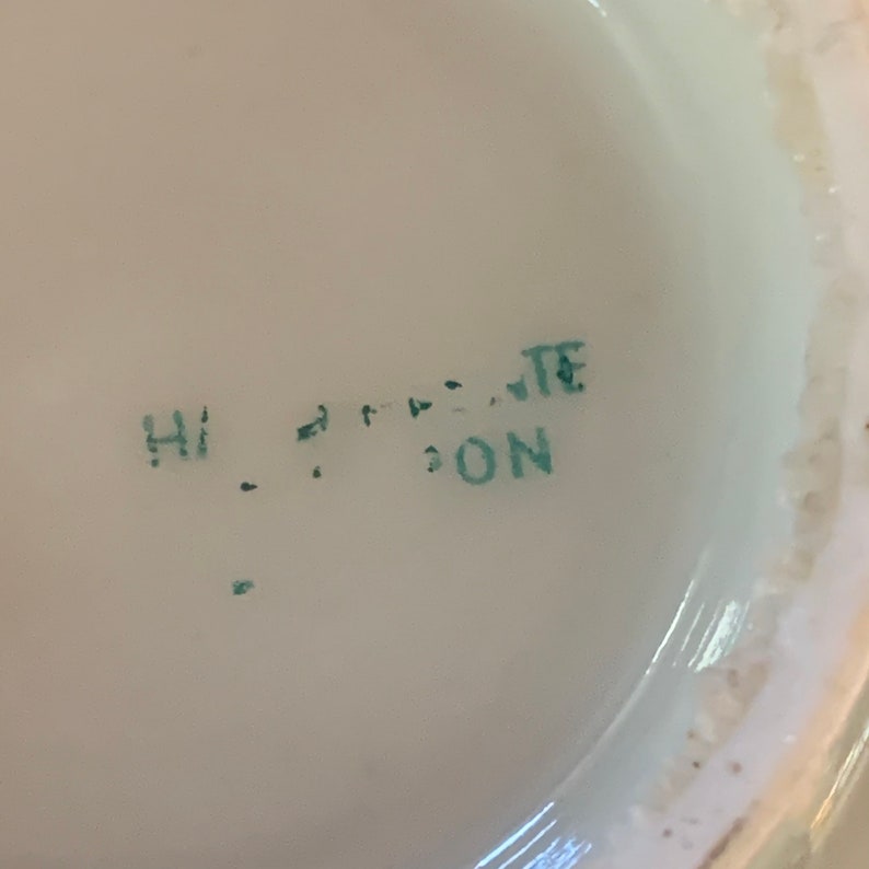 May include: Close-up of a green stamp on a white surface that reads "HI ... TE ... DON".