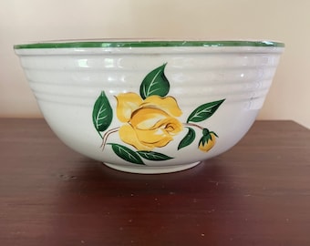 May include: White ceramic mixing bowl with a yellow rose and green leaf design. The bowl has a green rim and horizontal ridges around the exterior. A classic kitchenware item.