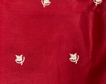 May include: Red fabric with a white floral pattern. The fabric has a subtle texture and a slightly shiny finish.