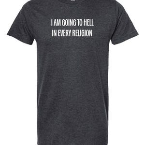 Puede incluir: Una camiseta de manga corta en color gris jaspeado oscuro con el texto blanco "I AM GOING TO HELL IN EVERY RELIGION" impreso en una fuente sans-serif en el pecho. La prenda tiene un cuello redondo y un corte recto estándar.