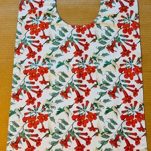 May include: A white bib with a red and green hummingbird and flower pattern.