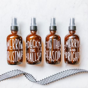 May include: Four brown glass spray bottles with white lettering. The bottles are labeled "Merry Christmas", "Deck the Halls", "Tis the Season", and "Merry and Bright".