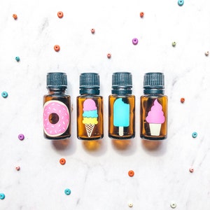 May include: Four small glass bottles with brown lids and colorful labels. The labels feature a donut, an ice cream cone, a popsicle, and a swirl ice cream cone.