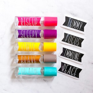 May include: Six clear glass roller bottles with colorful labels and black and white labels with the words "Rise Up", "Sleepy", "Owie", "Brave", "Breathe", "Tummy", "Focus", "Immune", and "Peace".