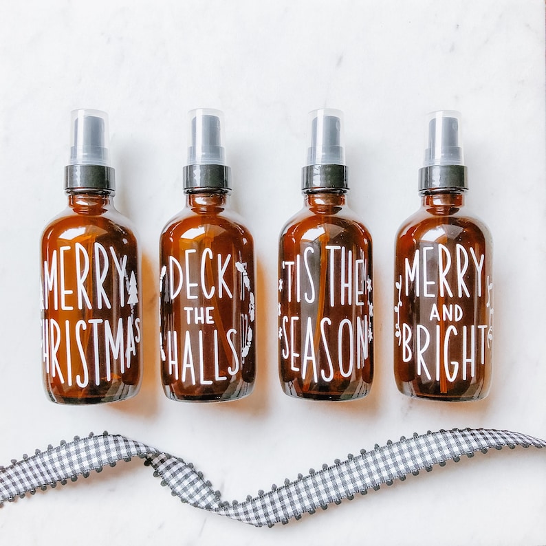May include: Four brown glass spray bottles with white lettering. The bottles are labeled "Merry Christmas", "Deck the Halls", "Tis the Season", and "Merry and Bright".