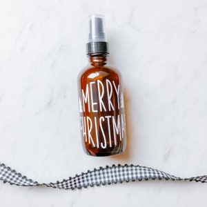 May include: A brown glass bottle with a black spray top and a white label that says "Merry Christmas".