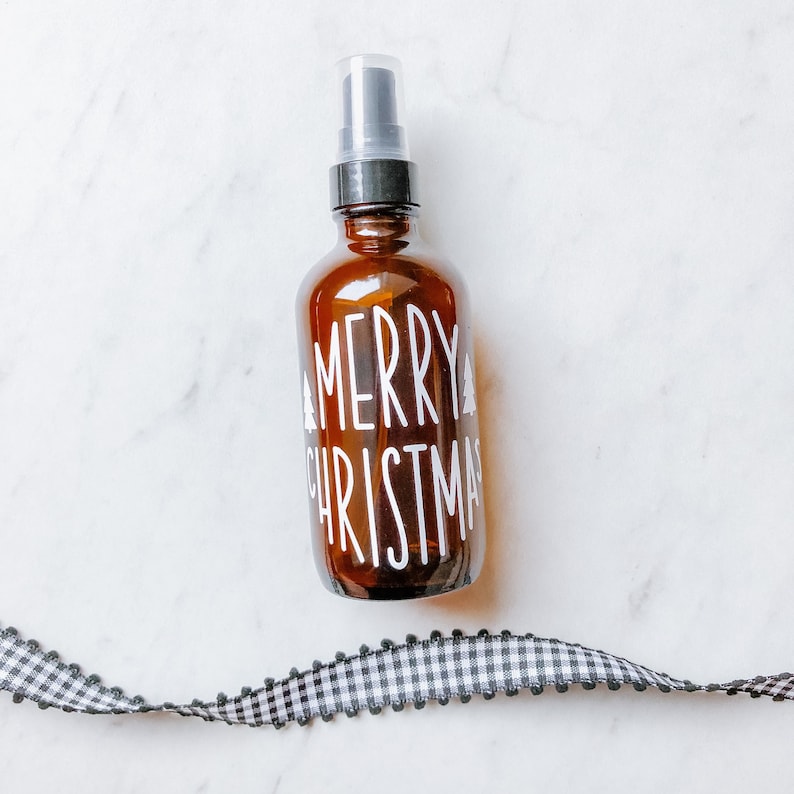 May include: A brown glass bottle with a black spray top and a white label that says "Merry Christmas".