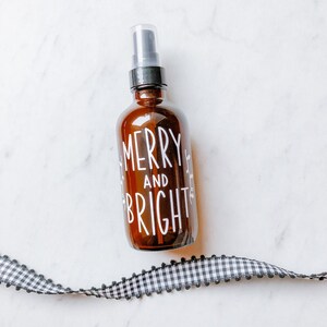 May include: A brown glass bottle with a black spray nozzle and a white label that says "Merry and Bright".