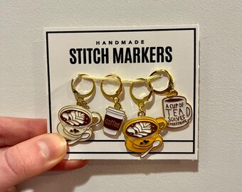 May include: Set of four gold stitch markers with coffee cup charms. The charms feature latte art, a coffee cup, and a teacup with the text "A cup of tea solves everything".