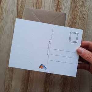 May include: A blank white postcard with a stamp area, a line for the address, and three lines for writing a message. The postcard has a small illustration of a mountain with a tent on top and the text "Roofs & Wilds" at the bottom.